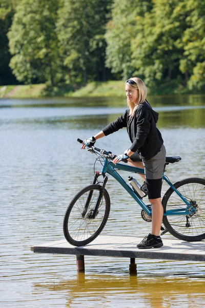 Góra kolarstwo młoda kobieta stojąc nad jeziorem — Zdjęcie stockowe