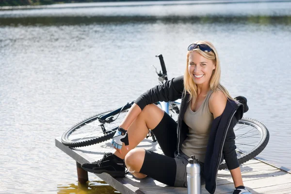 Sport biking young woman sitting by lake — Stock Photo, Image