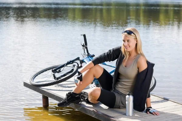 湖のそばに座ってスポーツ自転車に乗る若い女性 — ストック写真