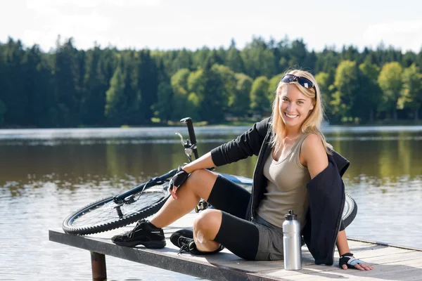 运动自行车年轻女子坐在湖边 — 图库照片
