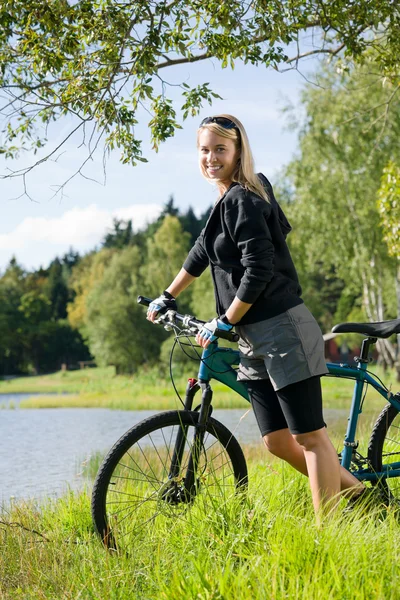 由湖山骑自行车的年轻女人放松 — 图库照片