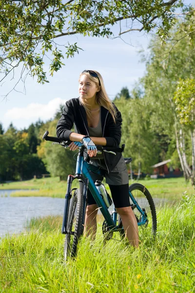 Dağ bisikleti genç kadın göl kenarında dinlenmek — Stok fotoğraf