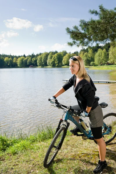 Horská cyklistika mladá žena relaxovat u jezera — Stock fotografie