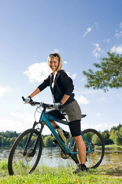 由湖山骑自行车的年轻女人放松 — 图库照片