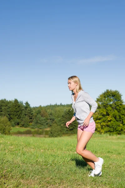 Běžecká mladá žena sportive louky slunečný den — Stock fotografie