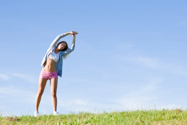 Stretching giovane donna sportiva prati giornata di sole — Foto Stock