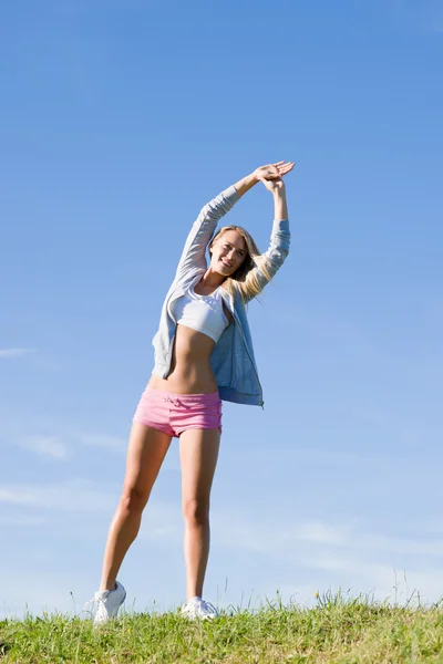 Estiramiento joven mujer deportiva prados día soleado —  Fotos de Stock