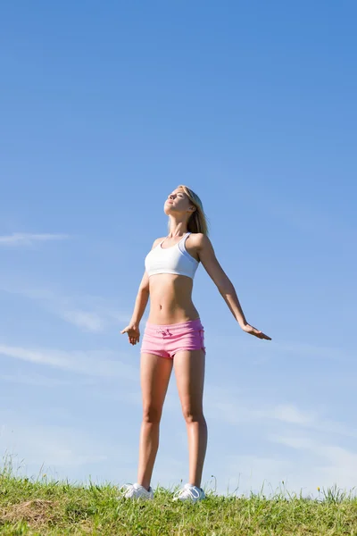 Stretching ung sportig kvinna ängar solig dag — Stockfoto