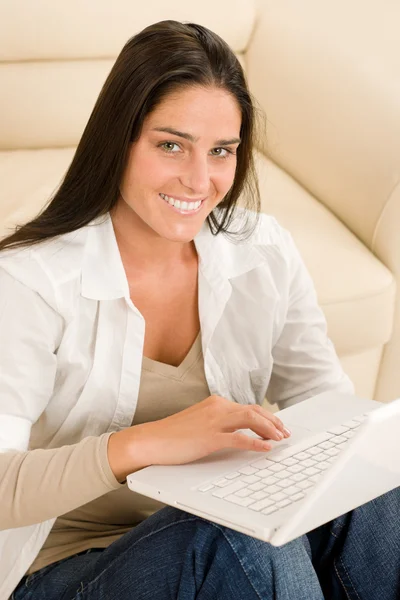 Kadın kanepe tebessüm ederek otururken dizüstü bilgisayar ile — Stok fotoğraf