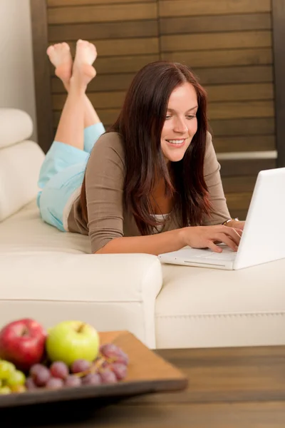Moderní obývací pokoj žena ležící na pohovce laptop — Stock fotografie