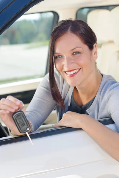 Attractive businesswoman in new car showing keys — Stock Photo, Image