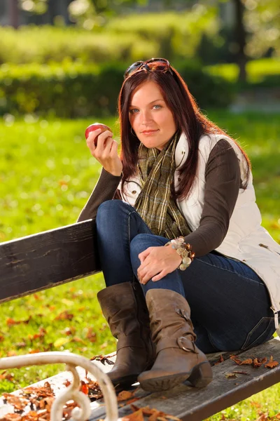 Осенью привлекательная женщина ест яблочный парк заката — стоковое фото