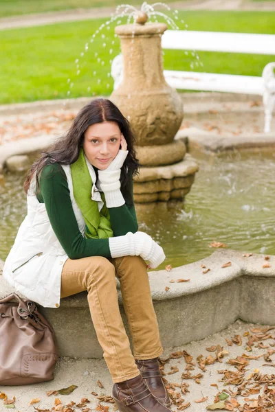 Autumn park young woman sit on fountain — Stock Photo, Image