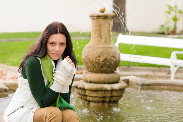 Осенний парк молодая женщина сидит на фонтане — стоковое фото