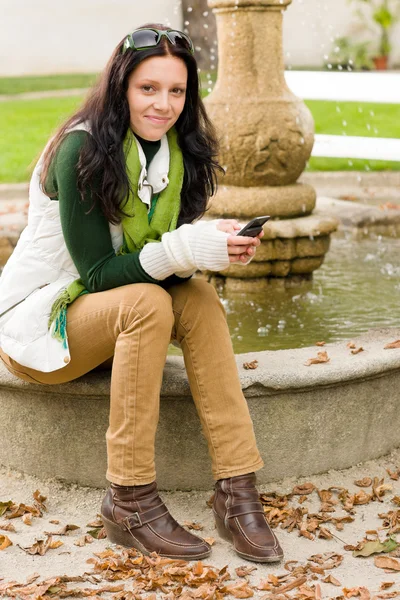Podzimní park lavička mladá žena drží telefon — Stock fotografie