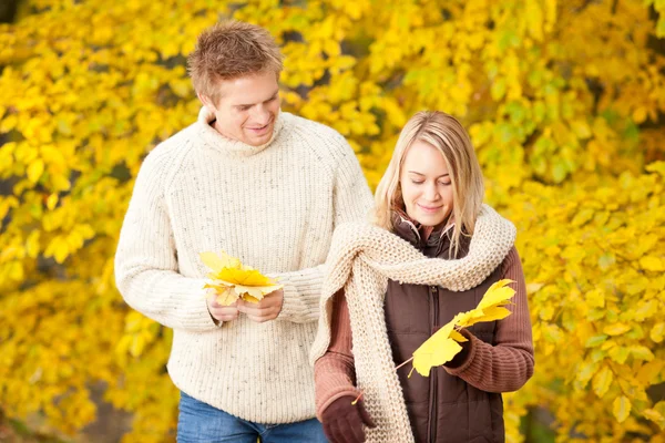 Outono feliz casal segurando folhas no parque — Fotografia de Stock