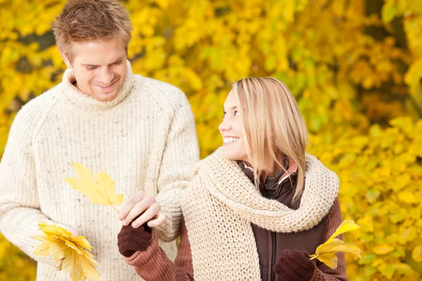 Autumn happy couple holding leaves in park — Stock Photo, Image
