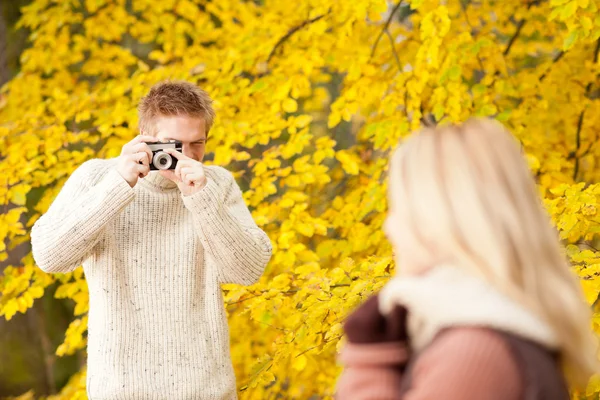 Herfst man maken foto's voor jonge vrouw — Stockfoto