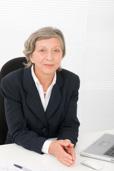 Senior mujer de negocios sonrisa sentarse detrás de escritorio de oficina —  Fotos de Stock