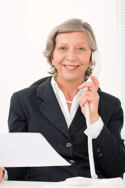 Старшая деловая женщина на телефоне держит пустой лист — стоковое фото