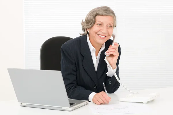 Seniorin lächelt hinter Schreibtisch — Stockfoto