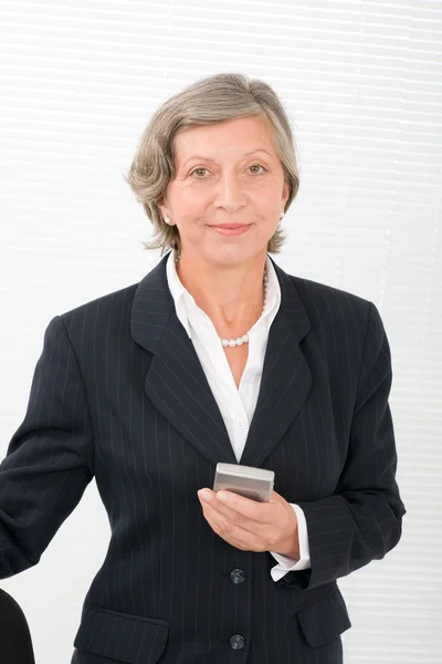 Старшая деловая женщина улыбается держать мобильный телефон — стоковое фото