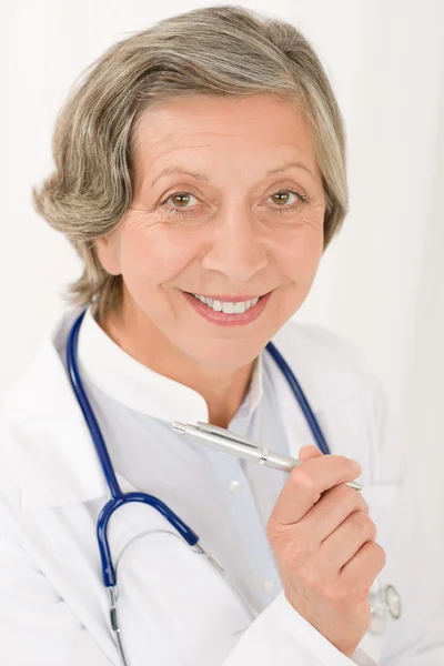 Médico sênior fêmea com estetoscópio sorrindo — Fotografia de Stock