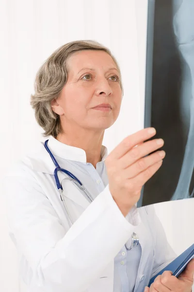 Старшая врач женщина смотрит на рентген — стоковое фото