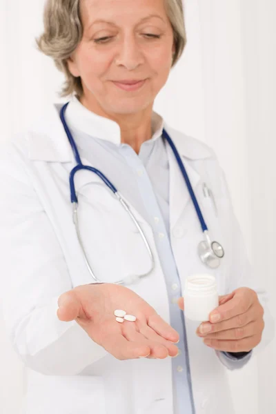 Ανώτερος γιατρός θηλυκό κρατήσει τα χάπια, κοιτάζοντας προς τα κάτω — Φωτογραφία Αρχείου