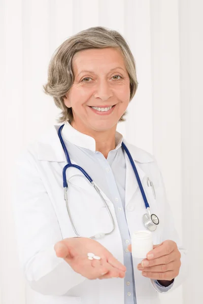 Médico médico sênior feminino segurar pílulas sorrindo — Fotografia de Stock