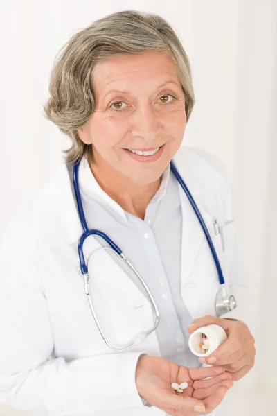 Врач старший женщина держит таблетки с улыбкой — стоковое фото