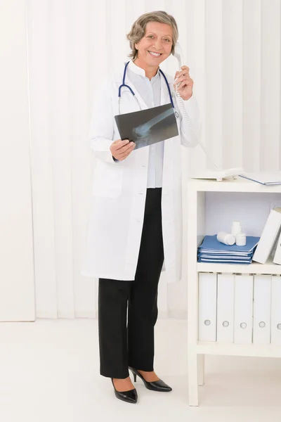 Starszy lekarz kobieta trzymać telefon i x-ray — Zdjęcie stockowe