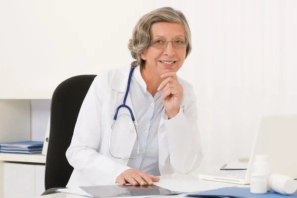 Senior arts vrouw zitten achter bureau — Stockfoto