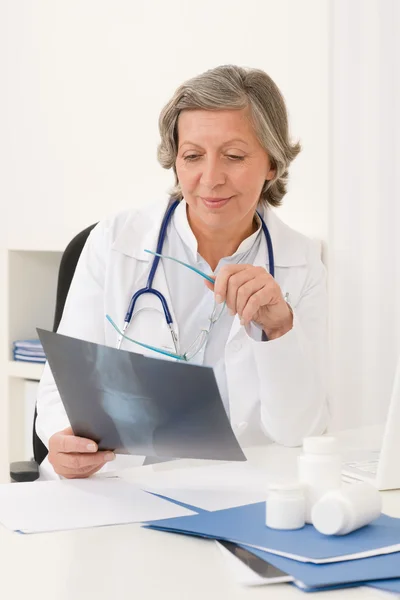 Starszy lekarz kobieta siedzieć za biurka — Zdjęcie stockowe
