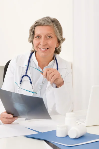 Starszy lekarz kobieta siedzieć za biurka — Zdjęcie stockowe