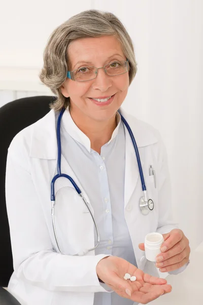 Médico médico senior hembra hold píldoras sonriendo — Foto de Stock