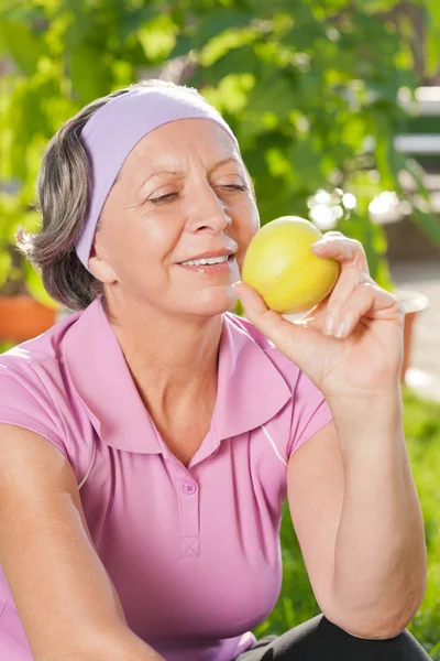 シニアの陽気な女性の笑顔は屋外のリンゴを食べる — ストック写真