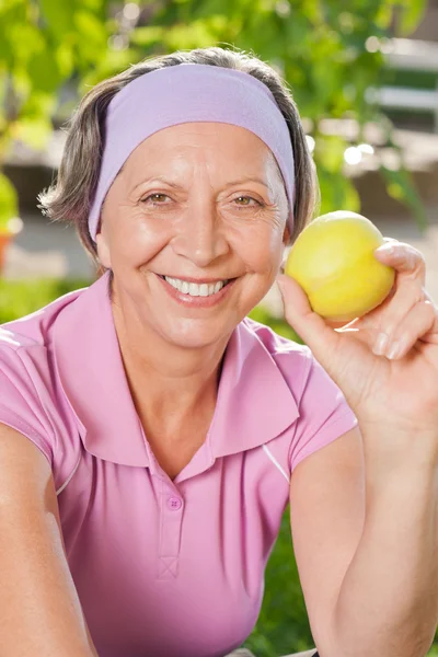 シニアの陽気な女性の笑顔は屋外のリンゴを食べる — ストック写真