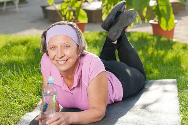 Старша спортивна жінка лежить на килимку сонячно — стокове фото