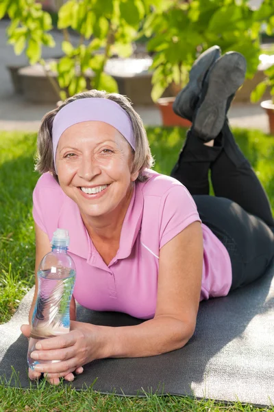 日当たりの良いマットに横たわっている年配の陽気な女性 — ストック写真