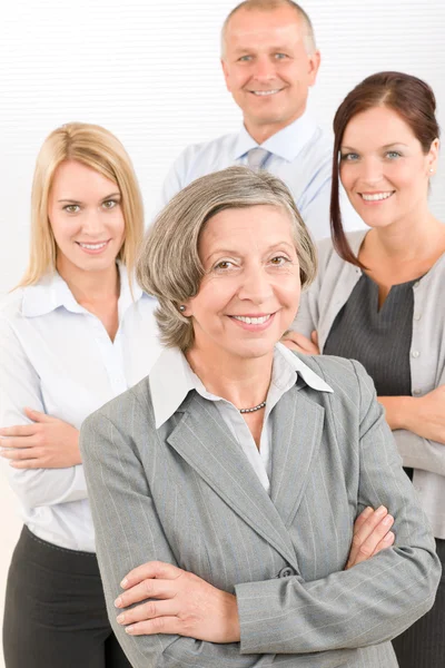 Mulher de negócios sênior com colegas nas costas — Fotografia de Stock