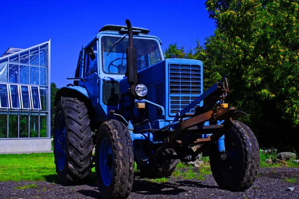 Покрашены в синий трактор, стоящий перед зданием — стоковое фото