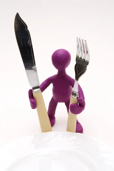Purple puppet of plasticine standing behind plate — Stock Photo, Image