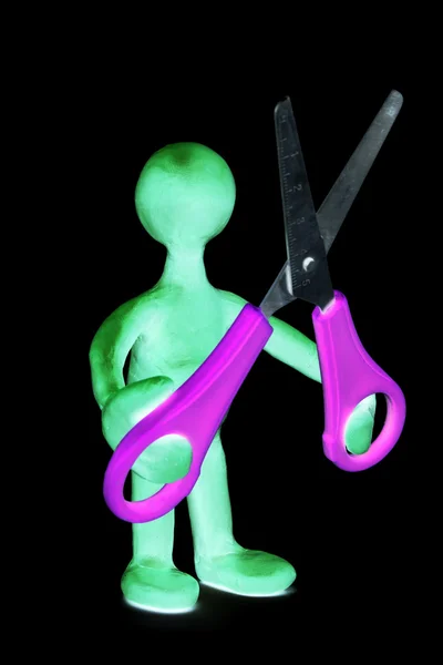 Shaded puppet of plasticine holding green scissors — Stock Photo, Image