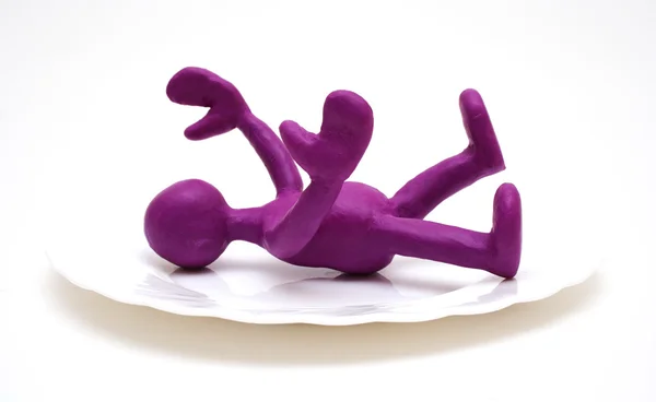 Purple puppet of plasticine laying on plate — Stock Photo, Image