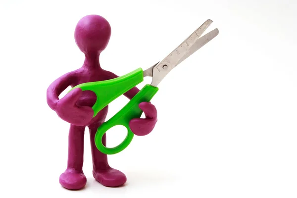 Purple puppet of plasticine holding green scissors — Zdjęcie stockowe