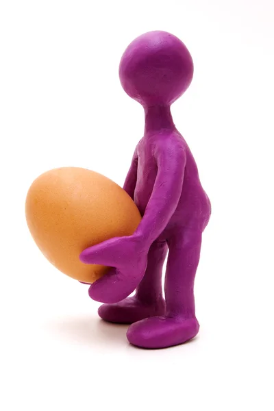 Marioneta púrpura de plastilina sosteniendo un huevo — Foto de Stock