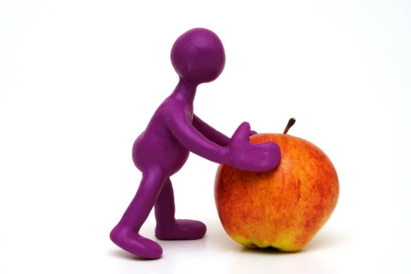 Purple puppet of plasticine pushing done apple — Stock Photo, Image