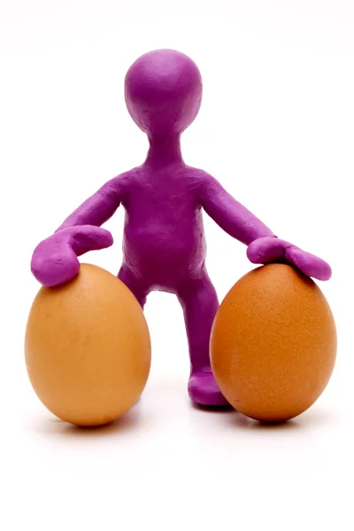 Paarse marionet van plasticine houden twee eieren — Stockfoto