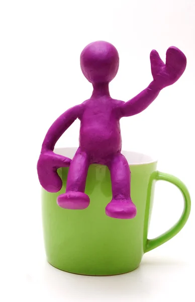 Marioneta púrpura de plastilina sentada en la taza — Foto de Stock